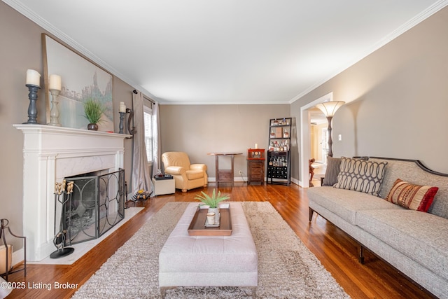 living room with a fireplace, crown molding, wood finished floors, and baseboards