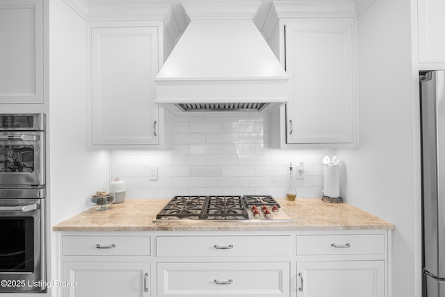 kitchen featuring premium range hood, backsplash, appliances with stainless steel finishes, and light countertops