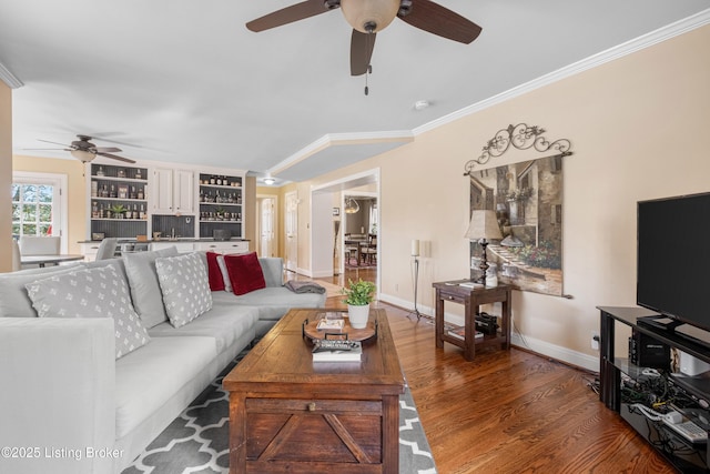 living area with wood finished floors, baseboards, and ornamental molding