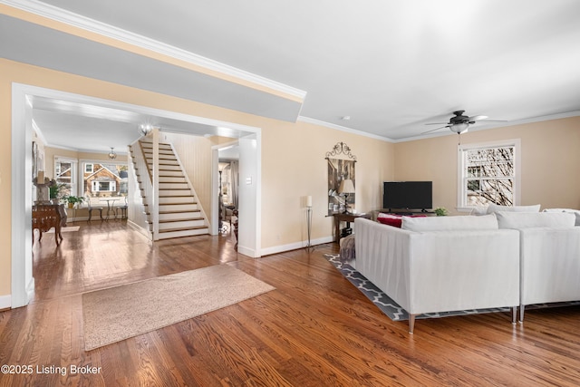 living area with ornamental molding, a ceiling fan, wood finished floors, stairway, and baseboards