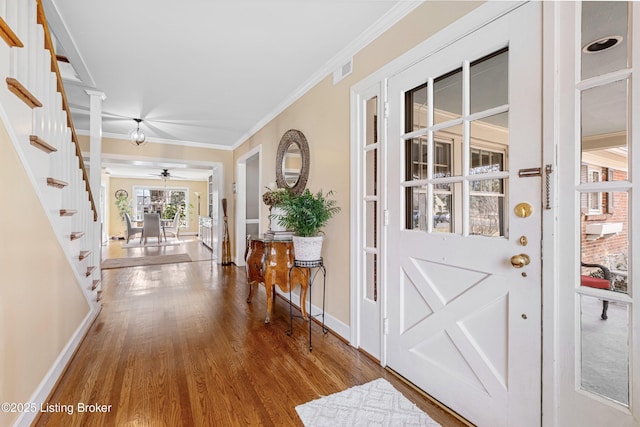 entrance foyer with wood finished floors, stairs, baseboards, and ornamental molding