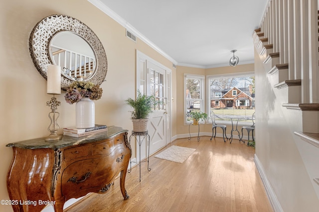 foyer with visible vents, wood finished floors, baseboards, and ornamental molding