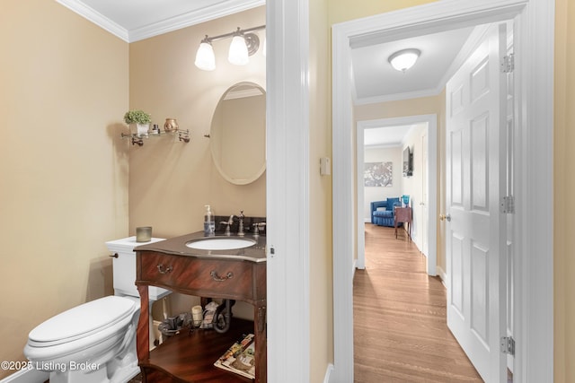 bathroom with toilet, ornamental molding, wood finished floors, baseboards, and vanity