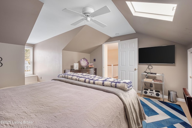 carpeted bedroom featuring vaulted ceiling with skylight, a ceiling fan, and baseboards