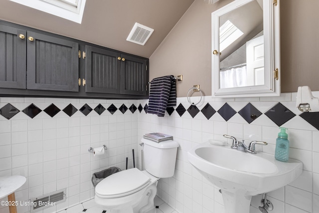 bathroom with visible vents, vaulted ceiling with skylight, toilet, and a sink