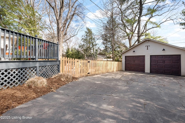 view of side of property featuring an outdoor structure, fence, and a detached garage