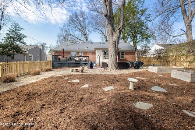 back of house featuring fence private yard, brick siding, a vegetable garden, and a deck