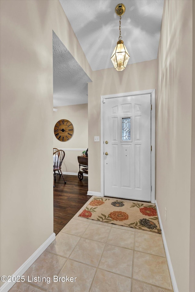 tiled foyer featuring baseboards and a textured ceiling