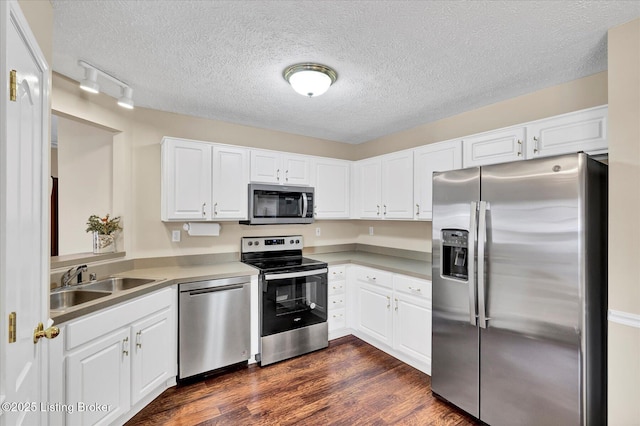 kitchen with stainless steel appliances, dark wood-style floors, a textured ceiling, white cabinetry, and a sink