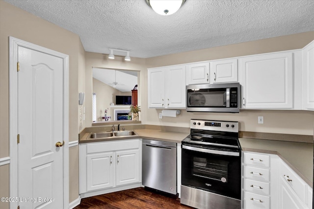 kitchen featuring dark wood-type flooring, white cabinets, appliances with stainless steel finishes, and a sink