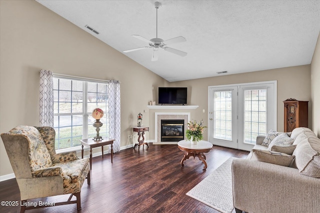 living room with dark wood finished floors, visible vents, a fireplace, and vaulted ceiling