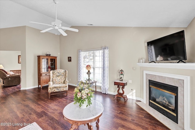 living room featuring a tiled fireplace, lofted ceiling, wood finished floors, and baseboards