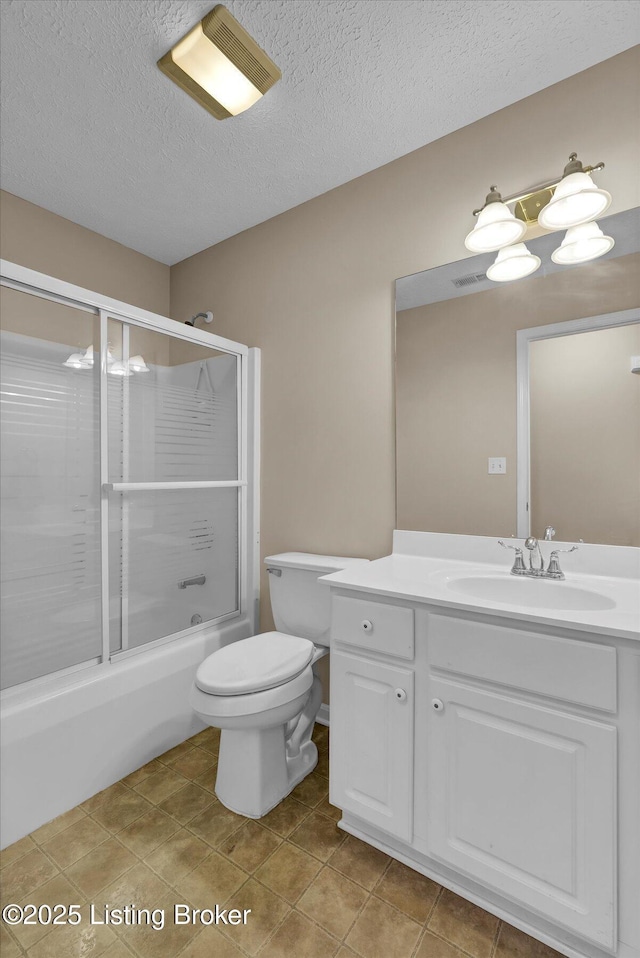 full bathroom featuring vanity, bath / shower combo with glass door, tile patterned flooring, a textured ceiling, and toilet