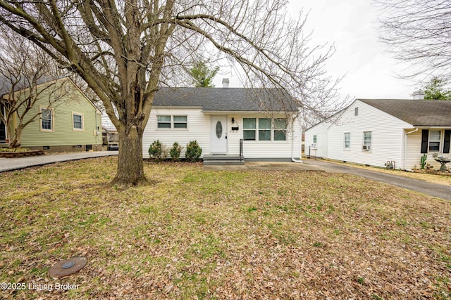 ranch-style home with a chimney, a front yard, and roof with shingles