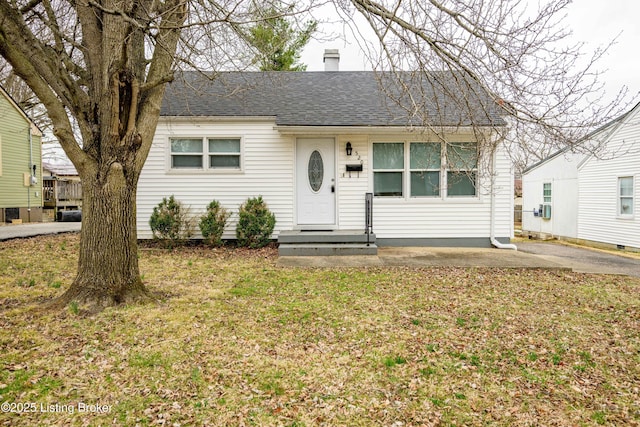 single story home featuring a shingled roof, a front yard, cooling unit, and a chimney