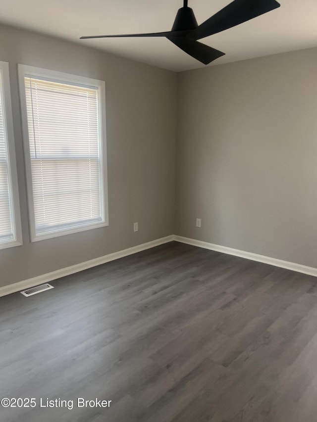 unfurnished room with a ceiling fan, dark wood-style flooring, and baseboards