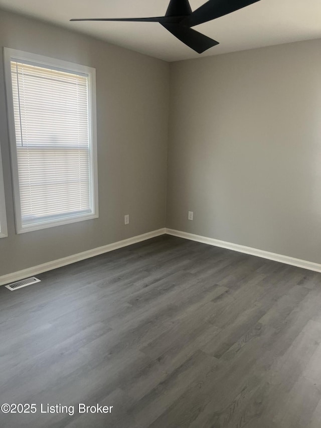 spare room with baseboards, visible vents, dark wood-style flooring, and ceiling fan