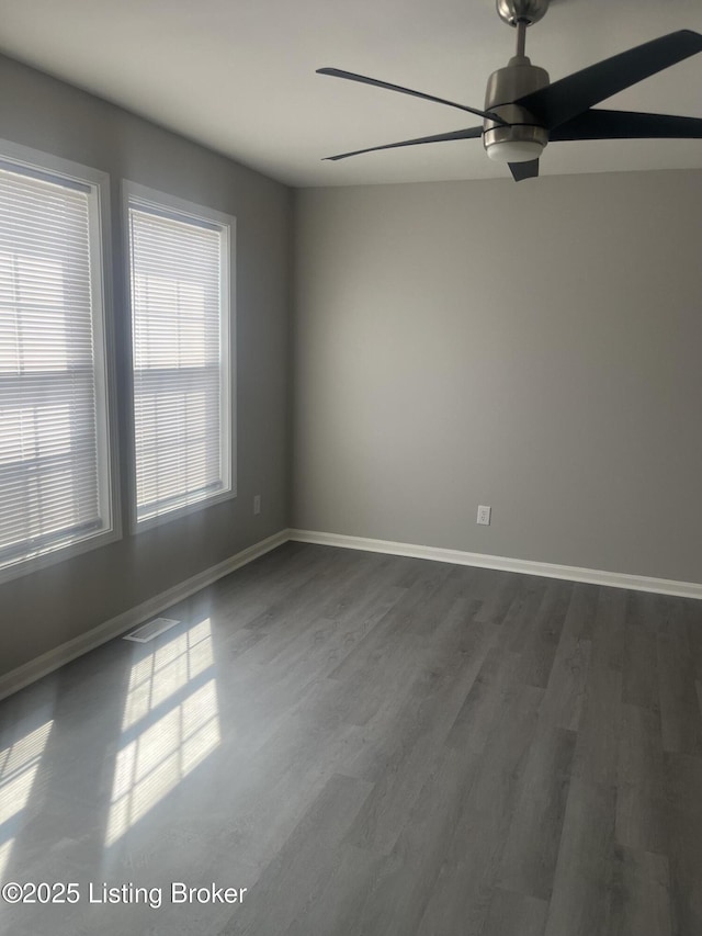 empty room with ceiling fan, visible vents, baseboards, and dark wood-style floors