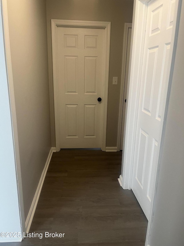 hallway featuring dark wood finished floors and baseboards