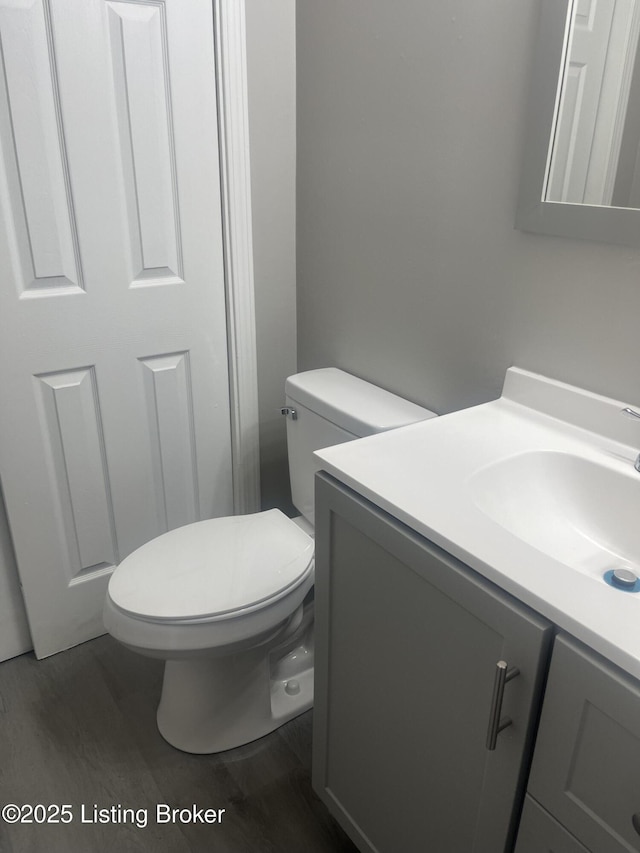 bathroom with toilet, wood finished floors, and vanity