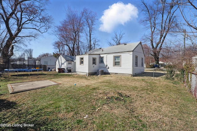 rear view of property featuring a trampoline, central AC, a fenced backyard, a yard, and a patio area