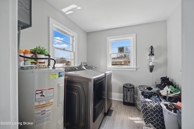 laundry room with baseboards, washing machine and clothes dryer, laundry area, water heater, and light wood-style floors