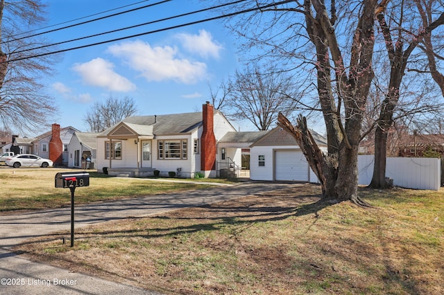 view of front of property with dirt driveway, fence, a front yard, a chimney, and an attached garage