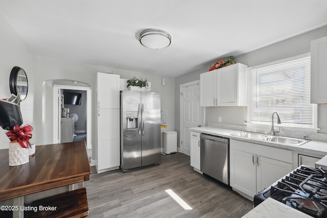 kitchen with light wood-style flooring, a sink, light countertops, appliances with stainless steel finishes, and white cabinetry