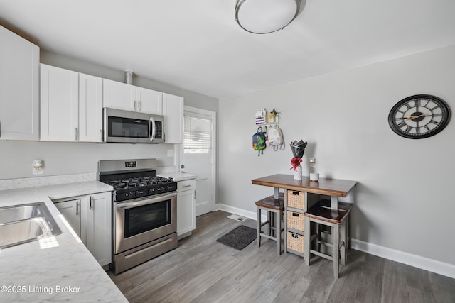 kitchen with white cabinets, stainless steel appliances, light countertops, and light wood-style floors