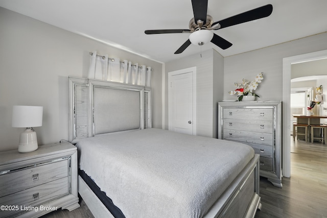 bedroom with arched walkways, ceiling fan, and wood finished floors