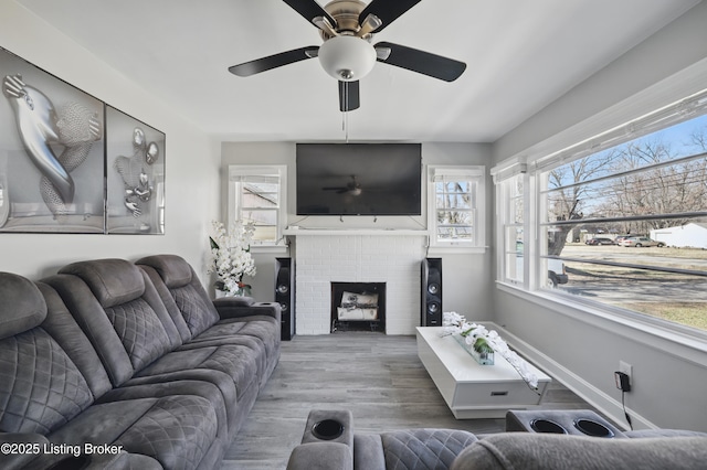 living area with a brick fireplace, wood finished floors, and baseboards