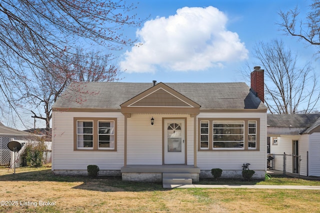 bungalow featuring a front lawn, fence, roof with shingles, and a chimney