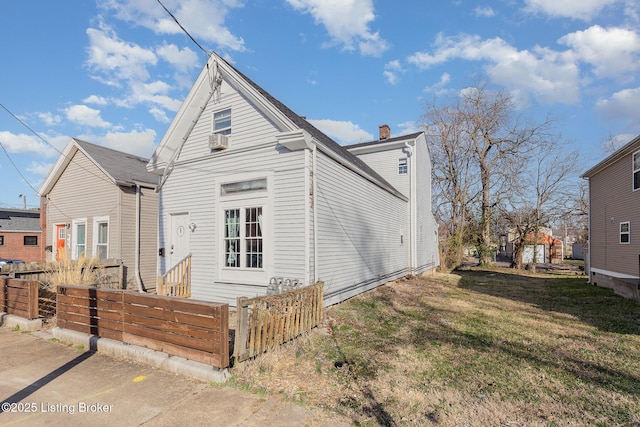 view of front facade featuring a chimney, a front yard, and fence