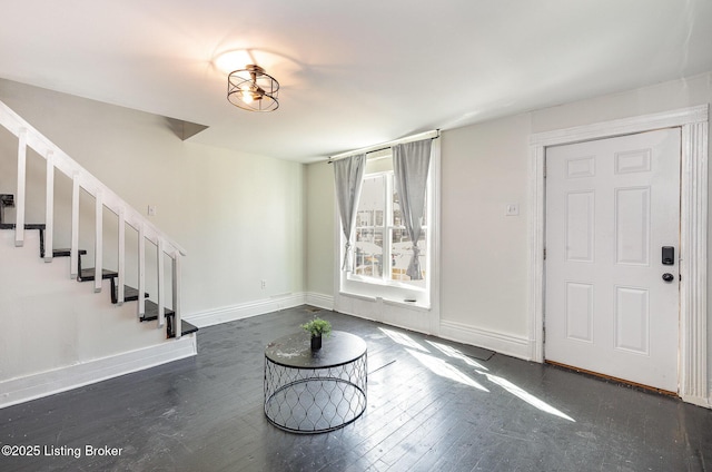 foyer entrance featuring dark wood-type flooring, stairway, and baseboards