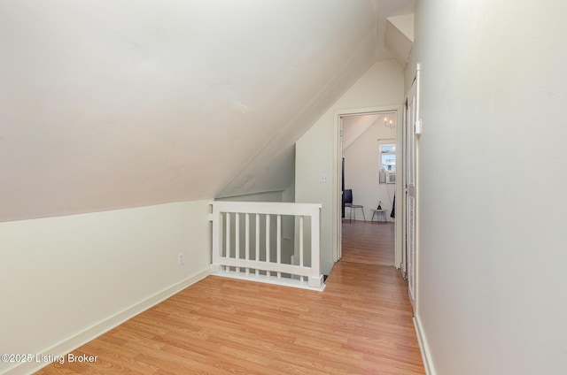 additional living space with vaulted ceiling, light wood-style flooring, and baseboards