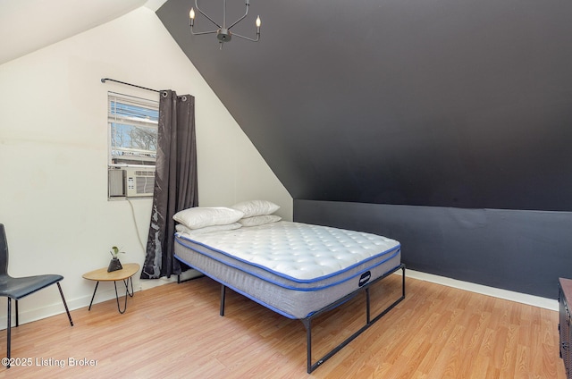 bedroom with cooling unit, baseboards, lofted ceiling, light wood-type flooring, and a chandelier