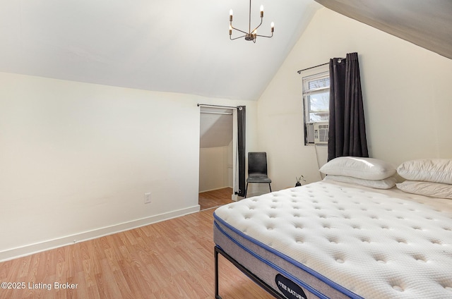 bedroom featuring light wood finished floors, an inviting chandelier, baseboards, and vaulted ceiling