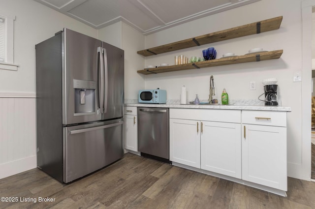 kitchen with appliances with stainless steel finishes, white cabinetry, dark wood-type flooring, and a sink