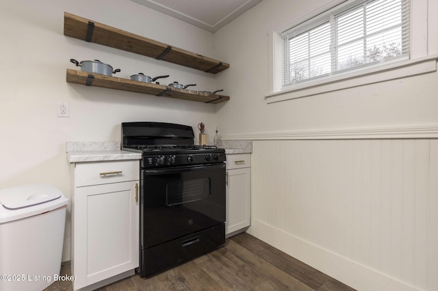 kitchen featuring a wainscoted wall, open shelves, light countertops, black gas range, and dark wood-type flooring