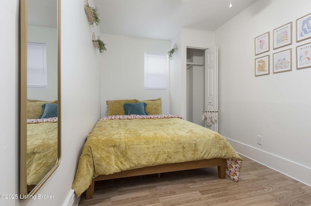 bedroom with a closet, baseboards, and wood finished floors