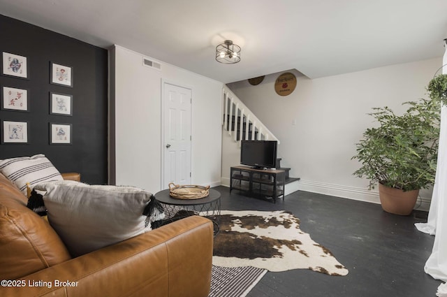 living area featuring visible vents, baseboards, concrete floors, and stairs