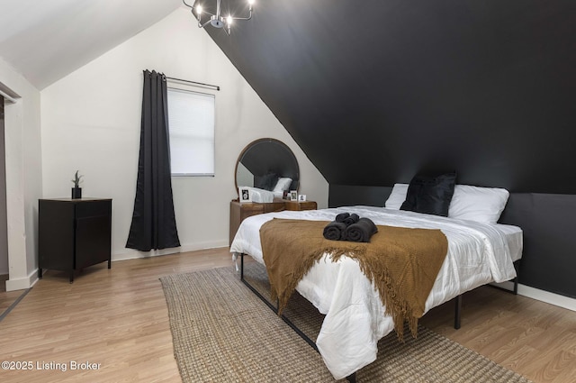 bedroom featuring lofted ceiling, baseboards, and light wood-type flooring