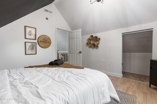 bedroom with lofted ceiling, light wood-style floors, and visible vents