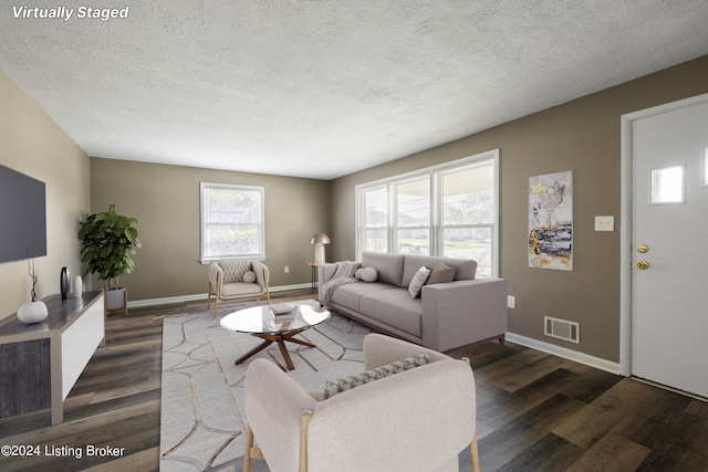 living area with visible vents, baseboards, a textured ceiling, and dark wood finished floors