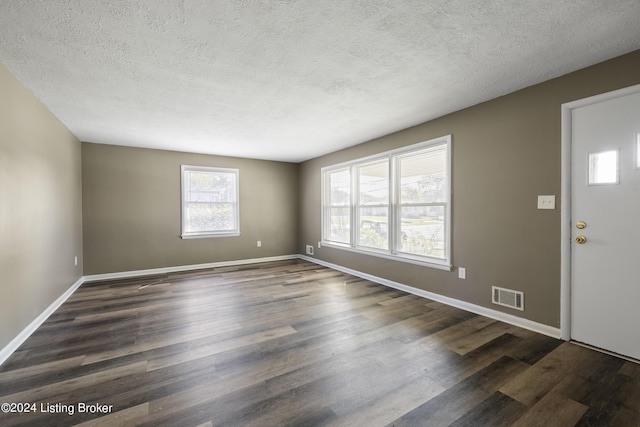 foyer with visible vents, baseboards, dark wood-type flooring, and a textured ceiling