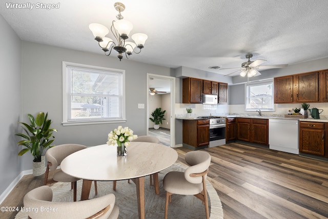 dining room with baseboards, a textured ceiling, dark wood-style flooring, and ceiling fan with notable chandelier