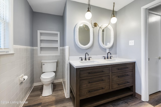 bathroom featuring double vanity, toilet, wood finished floors, and a sink