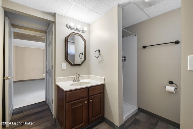 full bathroom with a drop ceiling, wood finished floors, and a stall shower