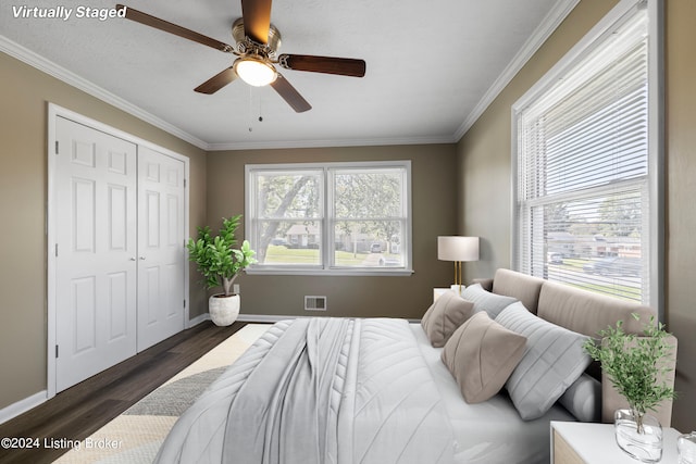 bedroom featuring wood finished floors, baseboards, visible vents, ornamental molding, and a closet