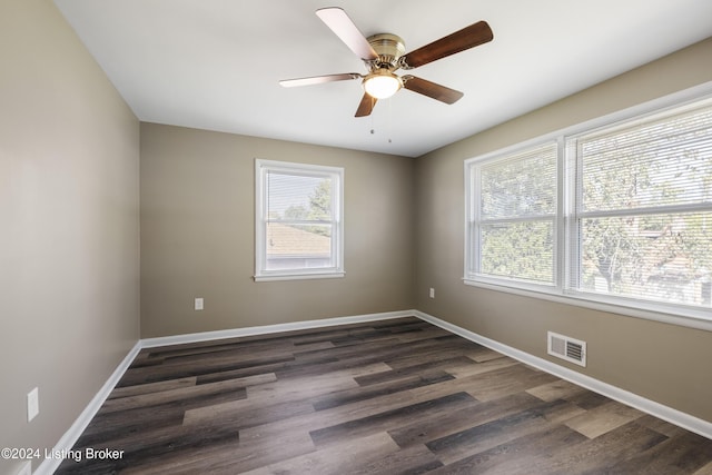 unfurnished room featuring dark wood-style floors, baseboards, visible vents, and ceiling fan